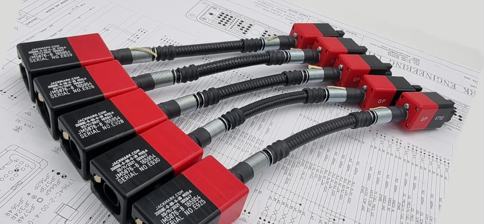 Five red rugged connectors with test leads on a schematic background
