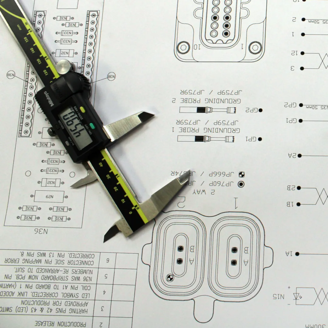 Five red and black test connectors on top of design drawing